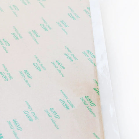 Close-up of 468MP Double Sided Adhesive Transfer Tape Sheets 12 By 12 Inches, pack of 5, showing protective layer and adhesive grid.