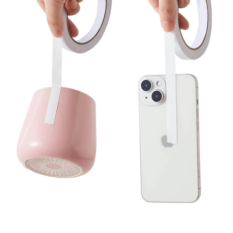 Double Sided Adhesive Tape One Quarter Inch Wide Four Rolls holding pink cup and smartphone, demonstrating strength and versatility.