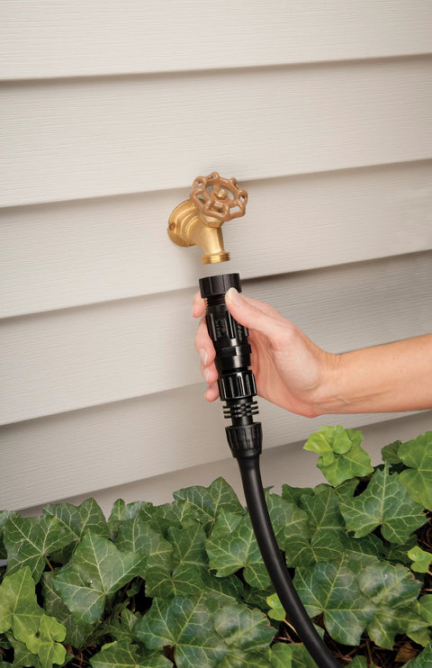 Hand installing Drip Irrigation Pressure Regulator 25 PSI For Garden Hoses And Drip Lines on outdoor faucet