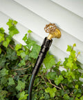Drip Irrigation Pressure Regulator 25 PSI connected to outdoor hose faucet among green foliage, displaying garden installation.