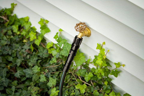 Drip Irrigation Pressure Regulator 25 PSI connected to outdoor hose faucet among green foliage, displaying garden installation.