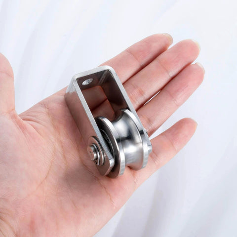 Person holding dual-bearing cable pulley wheel set for rope systems, wall or ceiling mounted, stainless steel construction