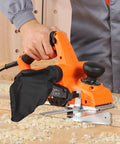 Effortlessly smooths stock, edges, and chamfers with a 7 Amp corded electric hand planer, featuring a 3 and 1 quarter inch cut width, 16800 RPM, adjustable depth, and dual blades for precise removal and a durable professional finish. Image shows a hand holding an orange electric hand planer on wood.