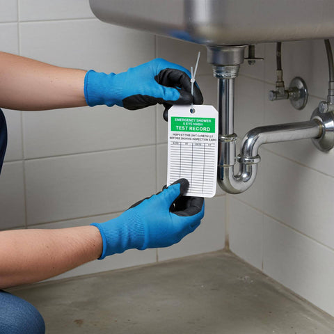 Person attaching an Emergency Shower And Eyewash Inspection Tags Set With 30 Double Sided Record Tags And 30 Zip Ties And Marker to pipe.