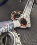 Applying Permatex 81950 Ultra Slick Engine Assembly Lube, 4 oz., Red to engine parts on black surface.