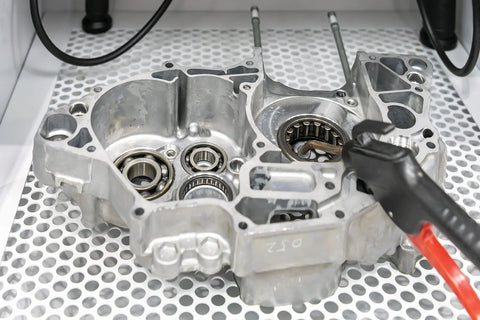 Close-up of a metal engine component on a perforated surface, featuring visible gears and mechanical parts in a workshop setting.