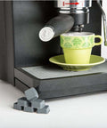 Self Adhesive Bumper Feet 0.780 In By 0.380 In Black Square Polyurethane Pads next to an espresso machine and cup