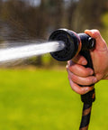 Person using Expandable Garden Hose Copper Bullet With Ten Pattern Thumb Spray Nozzle As Seen On TV 650 PSI Lead Free, spraying water