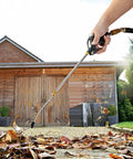 Extendable air blow gun with a 19 to 28 inch nozzle, blowing leaves in front of a wooden shed, visible hand holding the tool.