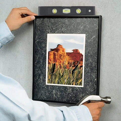 Person using 89-Piece Black Household Tool Set With 12 Pocket Tool Bag for hanging a picture frame.