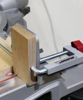 Milescraft fence clamp with 3/8 in. rod and aluminum body, red knob, mounted on a table saw fence clamping a wooden block.