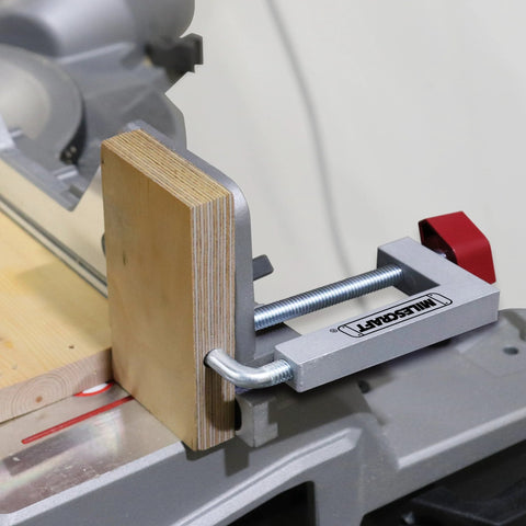 Milescraft fence clamp with 3/8 in. rod and aluminum body, red knob, mounted on a table saw fence clamping a wooden block.