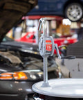 Fill-Rite SD62 Hand Pump Rotary 2-Vane Curved Spout on drum in auto repair shop with cars in background