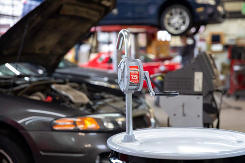 Fill-Rite SD62 Hand Pump Rotary 2-Vane Curved Spout on drum in auto repair shop with cars in background