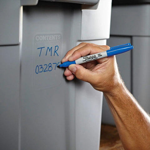 Hand using fine point permanent markers deliver bold, precise lines with quick-drying, odorless ink that resists fading and is waterproof on plastic bin.