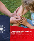A parent applying a bandage to a child's knee next to a blue First Aid Medical Supplies bag outdoors.