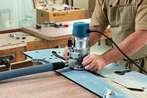 Woodworker using Fixed Base Router 2.25 HP 12 Amp Variable Speed 8000 to 25000 RPM for precise edge work on a table.