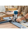 Person using Fixed Base Router 2.25 HP 12 Amp Variable Speed 8000 to 25000 RPM for precise edge work on wood panel.