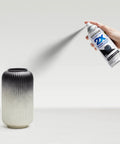 Person using Painter's Touch 2X Ultra Cover Spray Paint In Flat Black on a decorative ceramic vase, illustrating indoor DIY application.