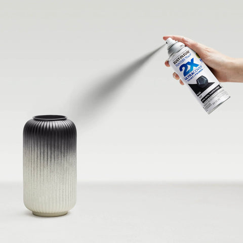 Person using Painter's Touch 2X Ultra Cover Spray Paint In Flat Black on a decorative ceramic vase, illustrating indoor DIY application.