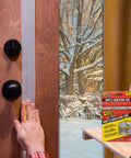 Applying Flex Seal Draft and Insulation Sealing Tape, 2 in x 16 ft, to a wooden door, with product box visible, snowy window view.