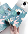 Person holding a floral and flamingo-patterned gift bag with a handle, demonstrating its design and functionality.