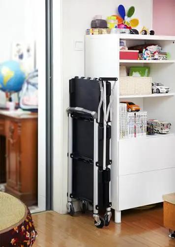 Pack N Roll Folding Collapsible Service Cart With 150 Lb Capacity, Locking Mechanism for Stability folded against a wall
