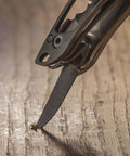 Close-up of Framework Mini 11 In 1 Multitool knife tip on wooden surface, showcasing open frame design and everyday utility.