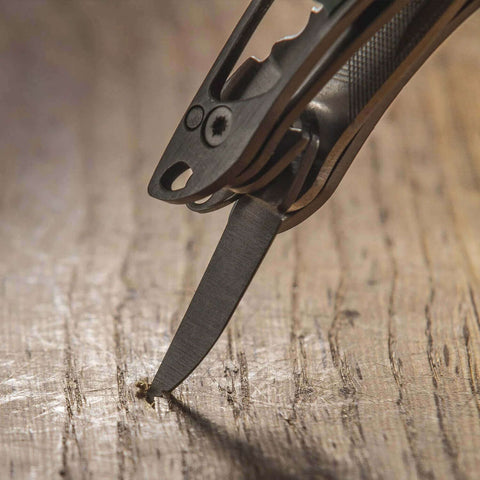 Close-up of Framework Mini 11 In 1 Multitool knife tip on wooden surface, showcasing open frame design and everyday utility.
