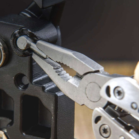 Close-up of Framework Mini 11 In 1 Multitool open frame with needle nose pliers gripping a metal part, showcasing detailed tool design.