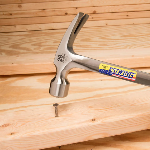 Framing Hammer 28 Oz Long Handle Straight Rip Claw With Milled Face And Shock Reduction Grip For Superior Leverage, Reduced Hand Fatigue, Precise Striking Power On Framing And Heavy Duty Carpentry, USA Made One Piece Forged Steel Construction E3 28SM hammer driving nail into wood.