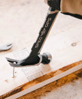 Framing Hammer 22 Oz Rip Claw Smooth Face With Shock Absorbing Grip Ballistically Balanced For Framing Demolition And Nail Setting On Tough Job Sites Plus Three Percent Donated To Veterans being used to pull a nail from wood surface.