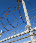 5" Pipe Track Wheel Galvanized installed on 1 7/8" chain link fence gate frame under blue sky with barbed wire
