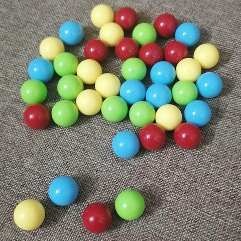 A mix of 60Pcs game replacement marbles balls in red, yellow, blue, and green on a textured surface, compatible with Hungry Hungry Hippos.