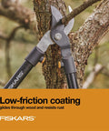 Heavy Duty 28 Inch Garden Loppers With Rust Resistant Bypass Steel Blade cutting a tree branch in a garden setting.