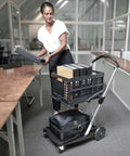 Person using Original German Made Collapsible Cart With Storage Crate Multiuse Folding Trolley For Shopping Hotels Catering Warehouse And Food Service Lightweight Aluminum Frame With Durable Polypropylene Cargo Box Black in office setting
