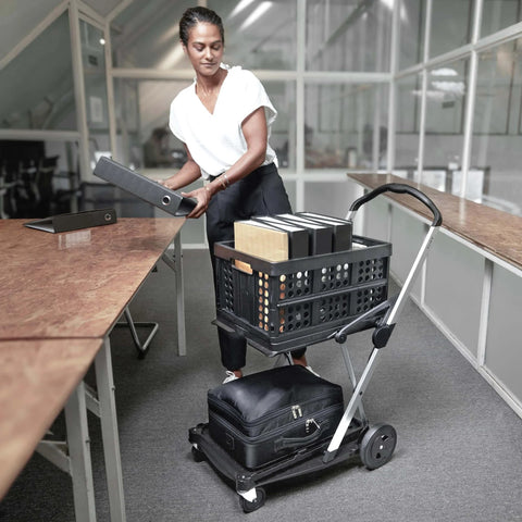 Person using Original German Made Collapsible Cart With Storage Crate Multiuse Folding Trolley For Shopping Hotels Catering Warehouse And Food Service Lightweight Aluminum Frame With Durable Polypropylene Cargo Box Black in office setting