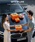 A couple exchanging a gift box on car hood with more gift boxes and flowers, labeled 'Gifts of Love.'