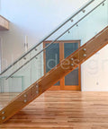 Stainless Steel Glass Clamp Standoffs Round Large Heavy Duty 2 Inch Inline Design installed on indoor staircase with wooden handrail.