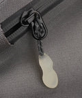 Close-up of glow-in-the-dark zipper pull on grey fabric, part of the 3 In 1 Nylon Zipper Puller Replacement Pack For Backpacks And Clothing.