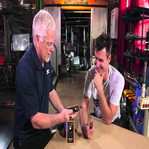 Two people using the GM TPMS Relearn Tool for 2006-2024 Chevy Buick GMC Opel Cadillac Vehicles 315/433 MHz in a garage setting