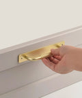 Close-up of hand pulling 2 Pack Gold 7 Inch Barn Door Handle For Sliding Closet Doors With Backplates and Drawer Pulls, installed on a surface.