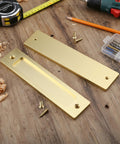 2 Piece Sliding Barn Door Closet Handles Set With Gold Coating, 6 inch rectangular finger pulls with screws on wooden surface