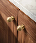 One Inch Gold Ball Cabinet Knobs Set Crafted From Solid Brass With Hand Brushed Finish installed on wood cabinets
