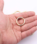 Hand holding a gold Three Quarter Inch durable zinc alloy carabiner from the Twenty Pack Trigger Spring Round Carabiner Clips Snap Hooks.