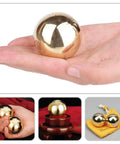 2Pcs Brass Exercise Ball 1.5 Inch Golden Solid Copper Metal Baoding Balls for Hand Therapy Stress Relief, Chinese Kung Fu Massage Acupressure Tool, displayed in hand, showcasing a smooth reflective surface.