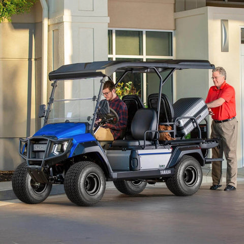 Blue golf cart with 8 Inch Golf Cart Wheels and Tires Combo Set of 4, parked with man loading bags, fits Club Car EZGO Yamaha