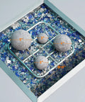12 Pack Gray Ceramic Balls, Mixed 4 Sizes Fireplace Balls displayed in fire pit with blue glass, highlighting different ball sizes.