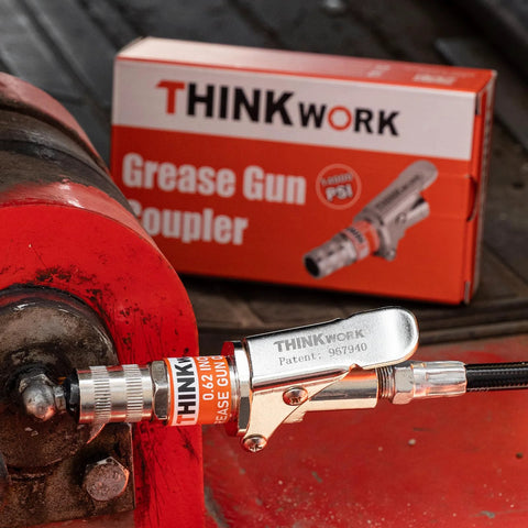 Hands Free Lock On Grease Gun Coupler With Cleaning Tool, 14000 PSI Quick Release connected to machinery, with packaging in view