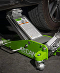 Green 3-Ton Hybrid Aluminum And Steel Low Profile Floor Jack With Dual Pump Pistons in use lifting a vehicle